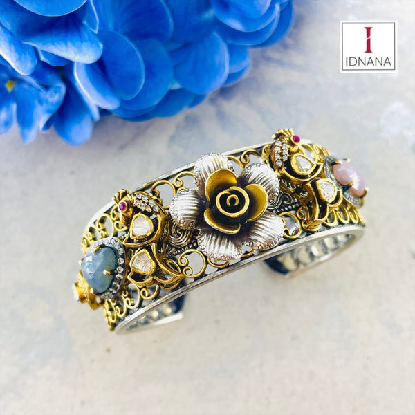 A DUAL TONE PINK AND BLUE SAPPHIRE MOISSANITE ROSE AND PEACOCK MOTIF HANDCUFF